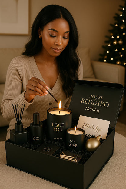 Woman lighting a candle in a 'House Beddieo' holiday gift set with Christmas tree in the background.